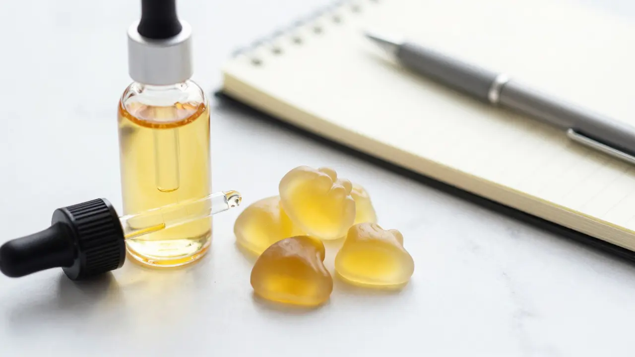 Nahaufnahme von CBD-Öl und Gummibärchen auf Marmor